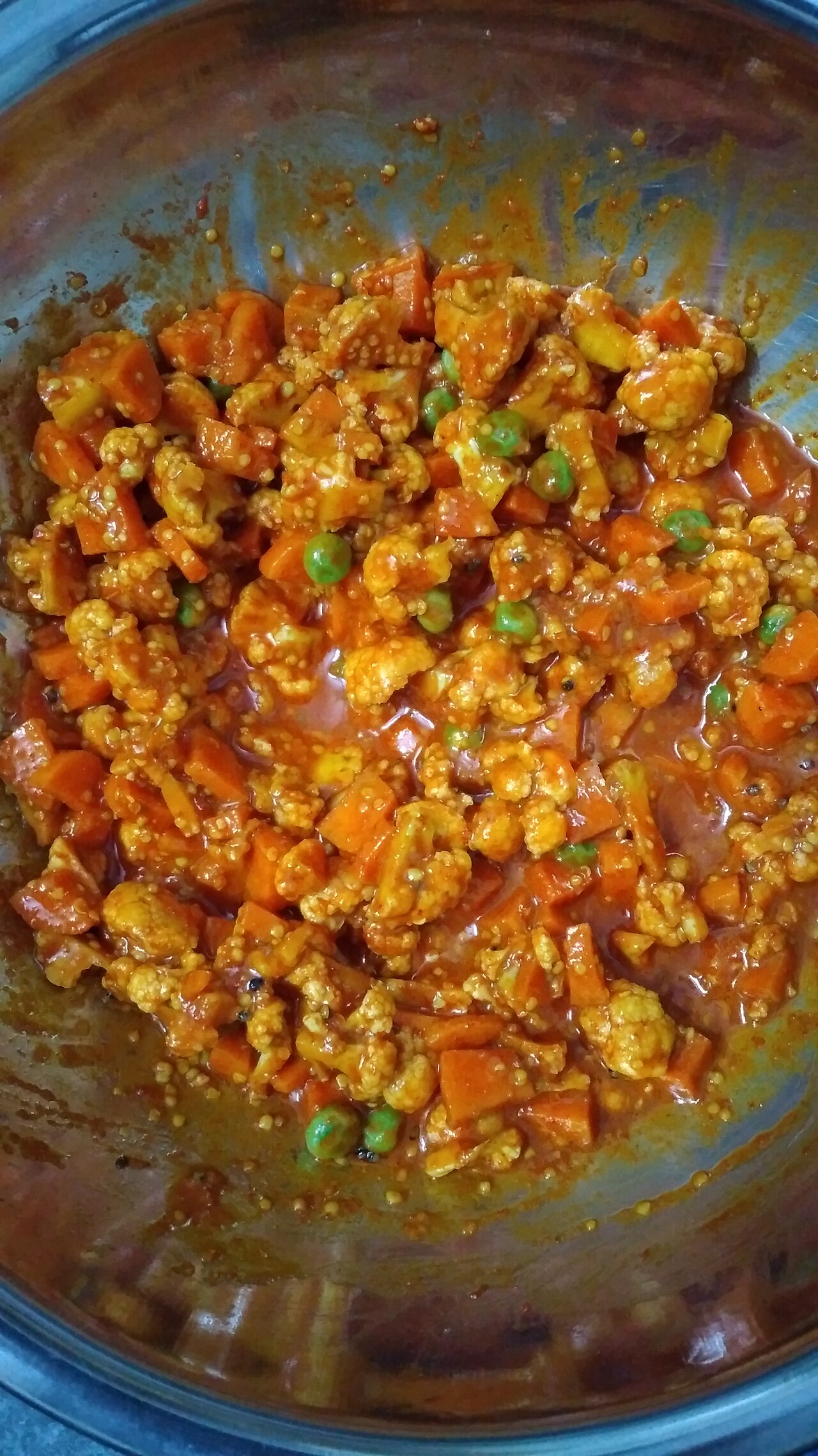 Close-up photograph of mixed vegetable pickle with carrots, cauliflower and peas in spiced oil